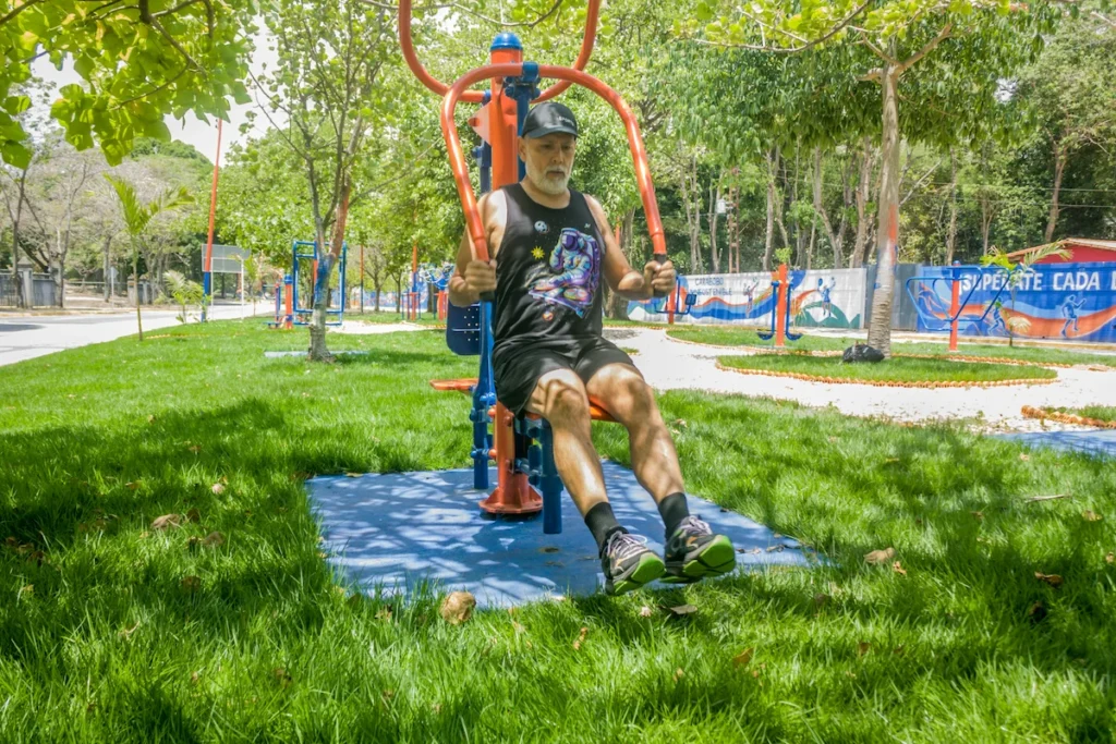 Persona mayor realizando ejercicio en un parque biosaludable para mejorar fuerza y movilidad.